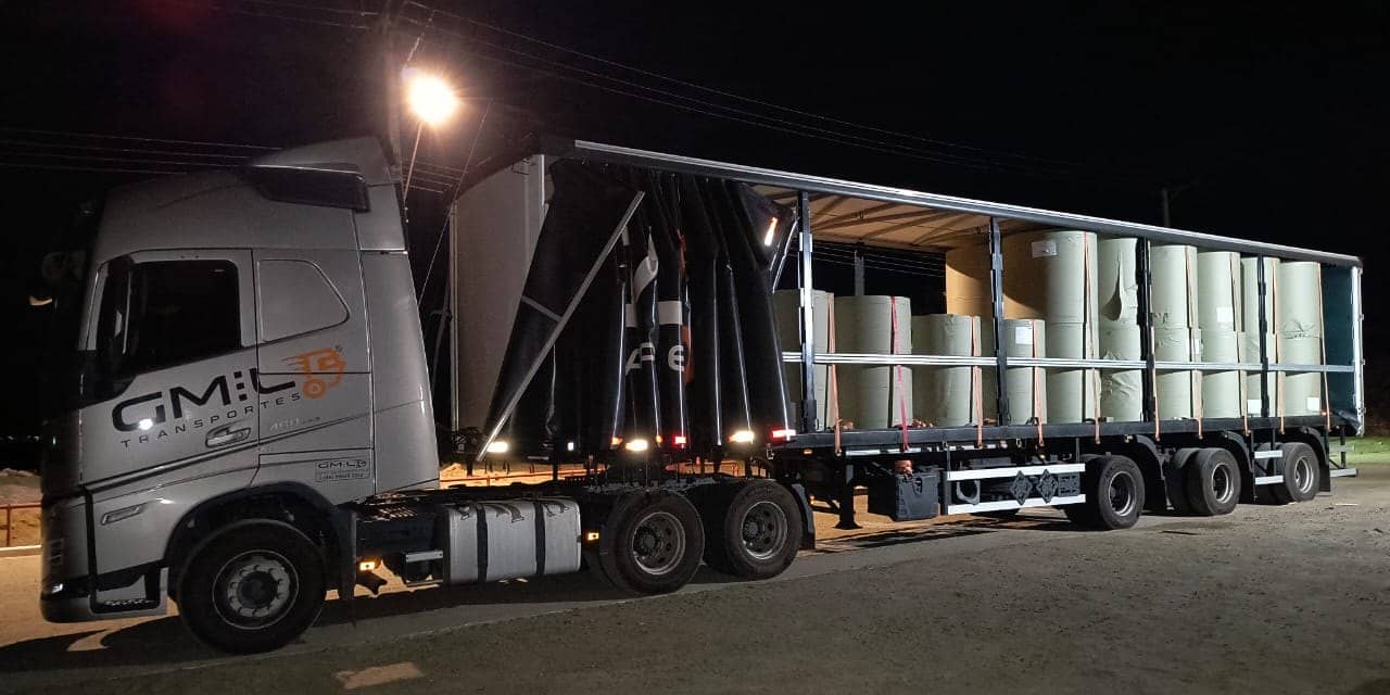 Carreta sider da GMIL com a lona aberta, carregada de bobinas, à noite